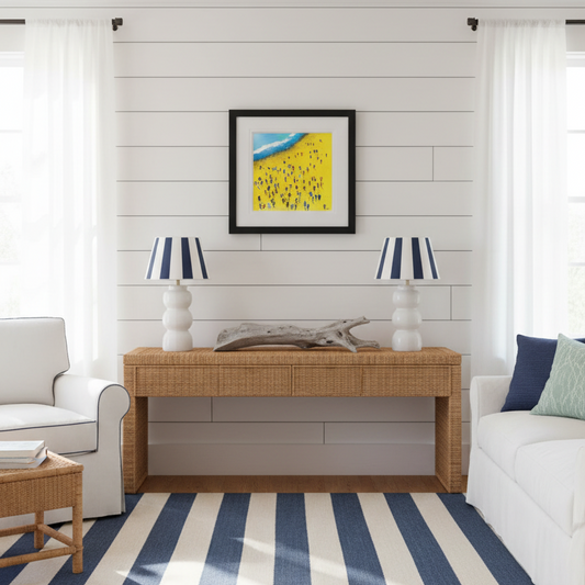 Beach Bums original painting in a living room with a wooden console table, white armchair, and striped rug.